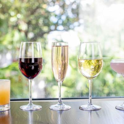Glasses of different drinks lined up on a table by a window