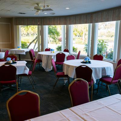 Interior, seating area with tables covered with white table cloths and red chairs.