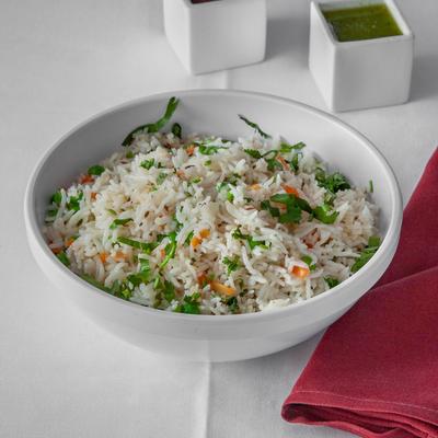 Pulao Rice bowl on a white tablecloth with a red napkin and small cubical bowls of chutney.