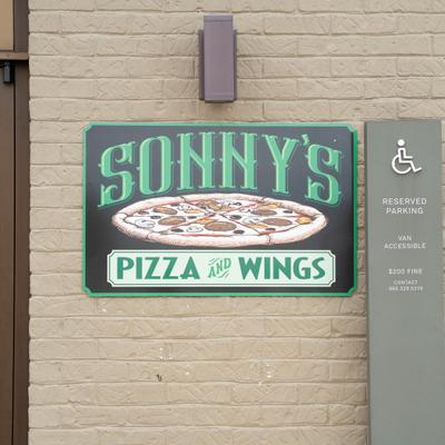 Restaurant's storefront sign featuring a stylized illustration of a whole pizza.