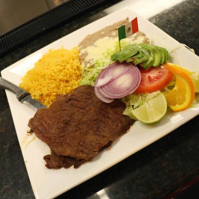 Carne Asada with rice, refried beans and salad on the plate.