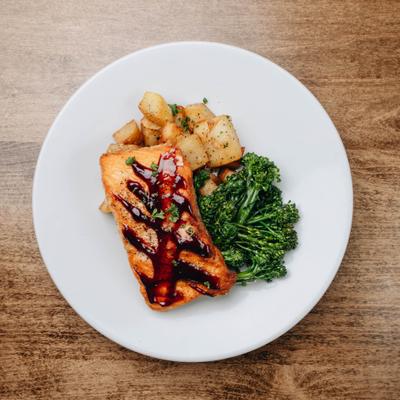 Glazed salmon served with potatoes and broccolini.