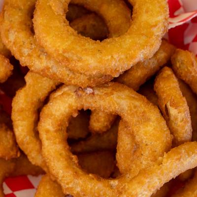 Crispy onion rings in a red basket, close up.