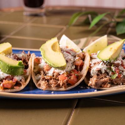 Pulled Pork tacos, with pico de gallo, cotija cheese, avocado, and cilantro drizzle.