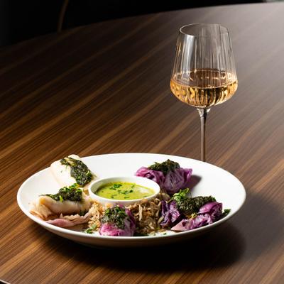 Cabbage rolls served with a dipping sauce and a glass of white wine.