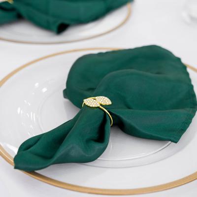 Dark green cloth napkin and a napkin ring on a white plate.