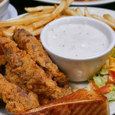 Fried chicken tenders served with fries, toast, and dipping sauce.