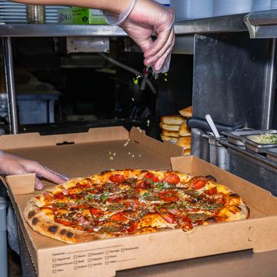 Person packing pizza in the box.