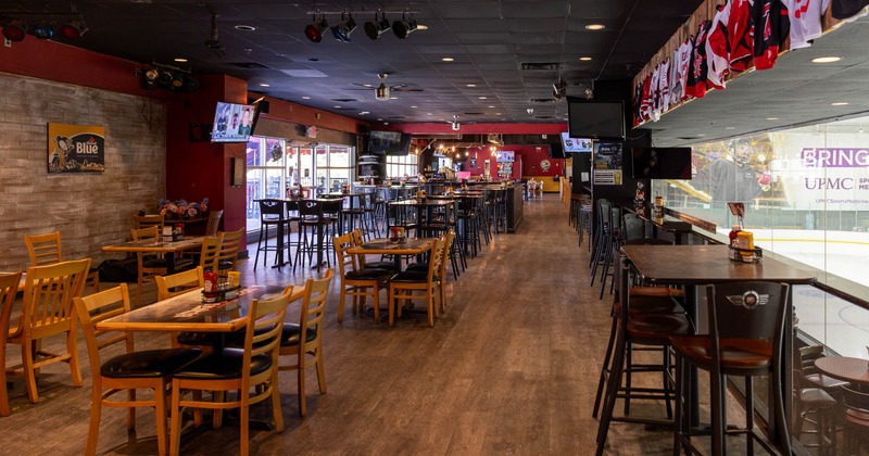 Sports bar with rink views, wooden tables, and hockey jerseys