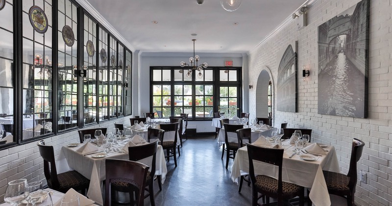 Interior, dining area, tables for four ready for guests, white brick walls, patio door