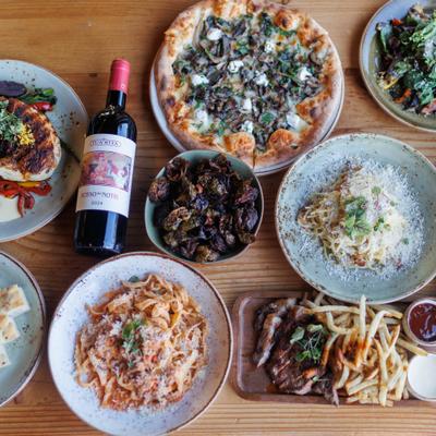 Assortment of dishes served on the table with a bottle of red wine.