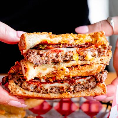 Hands holding a patty melt sandwich.