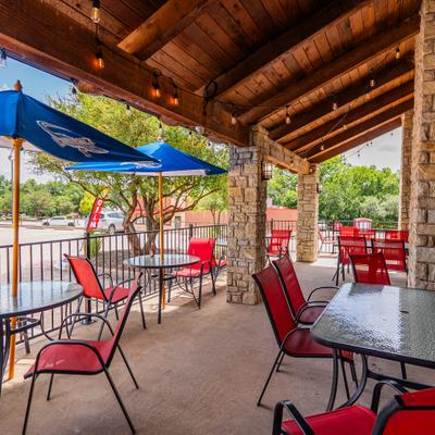Outdoor patio featuring a covered wooden ceiling, blue umbrellas and table seating.