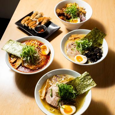 Three ramen bowls, a chicken bowl, and a plate with pork gyoza.