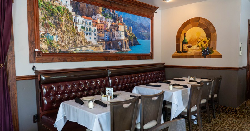 Interior with set tables and large framed picture of colorful coastal town
