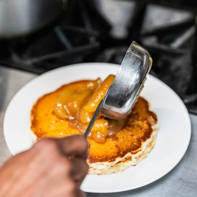 A hand topping pancakes with warm cinnamon apples.
