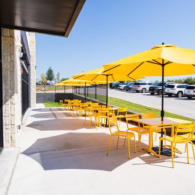The Brunch District, outdoor seating area  featuring yellow tables, chairs, and umbrellas.