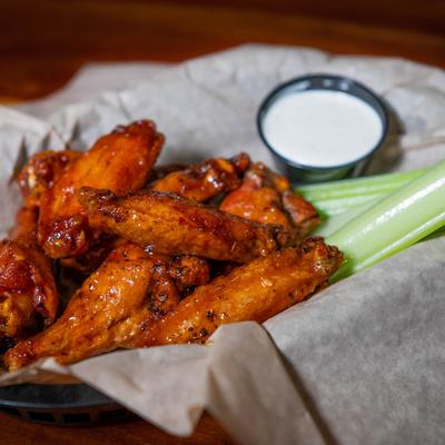 Chicken wings with celery sticks and ranch sauce.