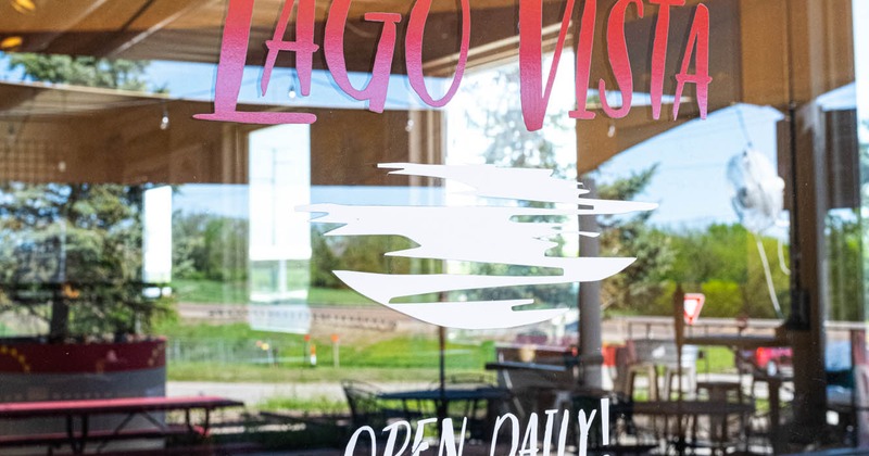 The reflection of the garden in the glass on the door with the logo and working hours