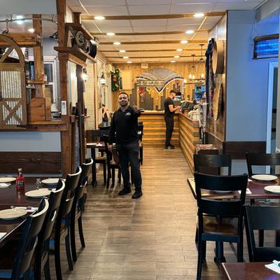 Restaurant interior with wooden decor and warm lighting, a smiling staff member.