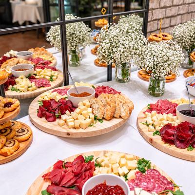Grazing table with round wooden boards arranged with cold cuts, cheeses,  and crackers.