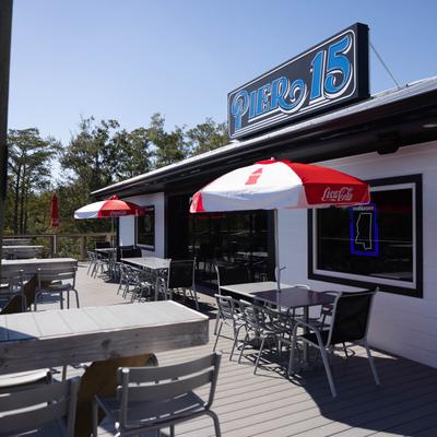 Outdoor seating area with tables, chairs, and parasols, surrounded by trees.