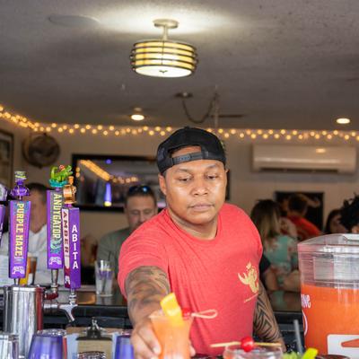 Bartender serving a cocktail drink behind counter.