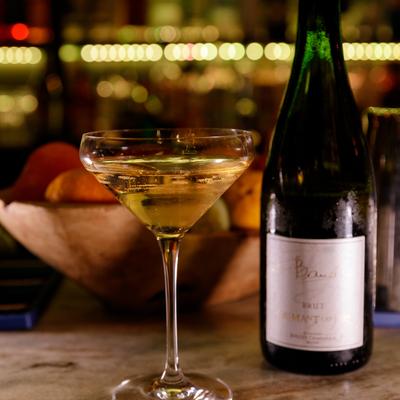 A bottle of champagne beside a full glass on a bar counter.