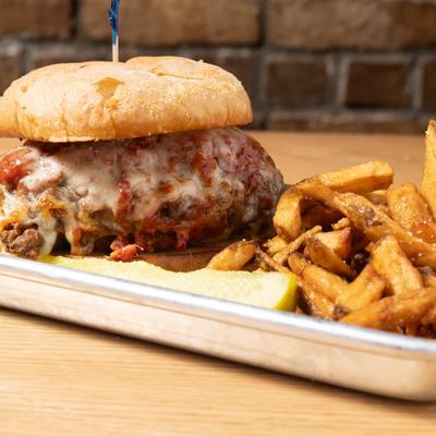 Chicken parmigiana sandwich served with fries and a pickle spear.