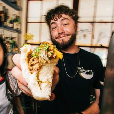 A person holds a meat-filled flatbread sandwich.