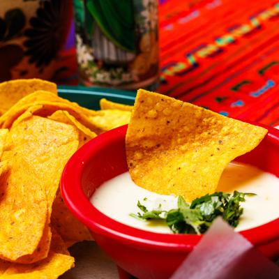 Queso dip topped with fresh cilantro and served with chips, close-up.