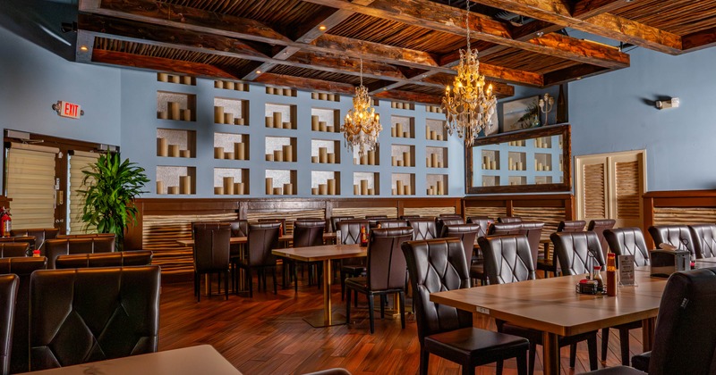 An elegant restaurant interior with chandeliers, dark wood furnishings, and decorative shelves