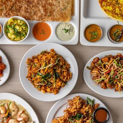 Indian food spread with roti, chutneys, noodles, and curries.