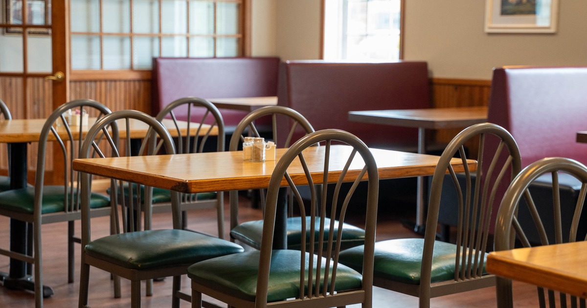 Interior - wooden tables, gray metal chairs with green seats, burgundy booths in the background