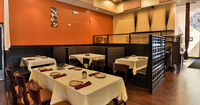 Interior with orange and cream walls, tables set with cream cloths, red napkins, cushioned chairs