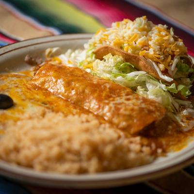 Enchilada smothered in red sauce, taco, rice, and beans.