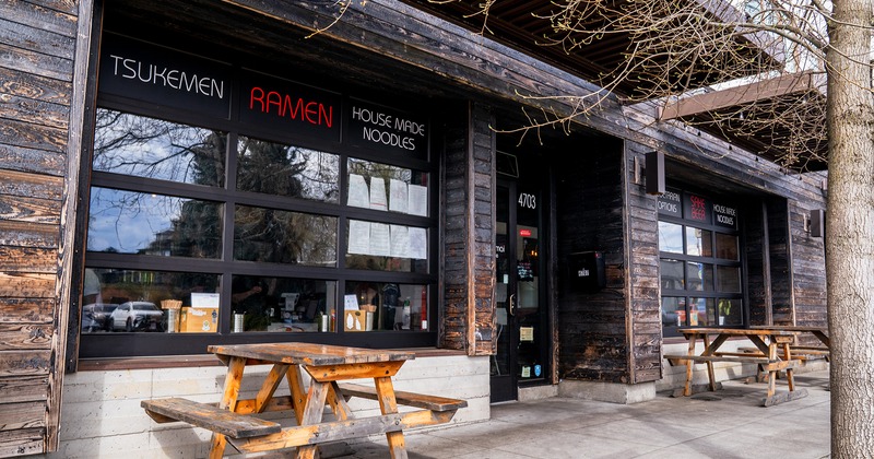 Outdoor seating area in front of the entrance, conjoined wooden tables and benches