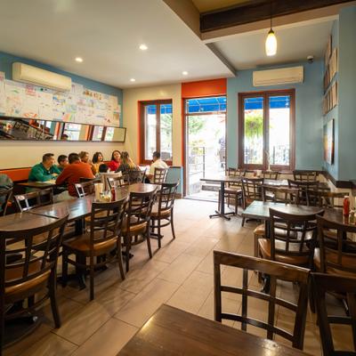 Interior, a casual ambiance with wooden tables and chairs, a brick wall, and colorful decor.