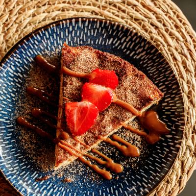 Churro cheesecake with sliced strawberries on top.