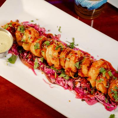 Buffalo shrimp served over shredded cabbage, with dip on the side.