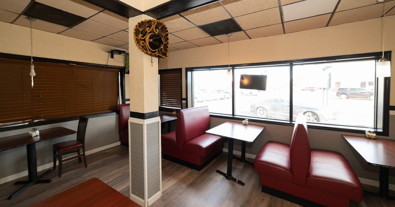 Interior of a restaurant with red leather booths and large windows.