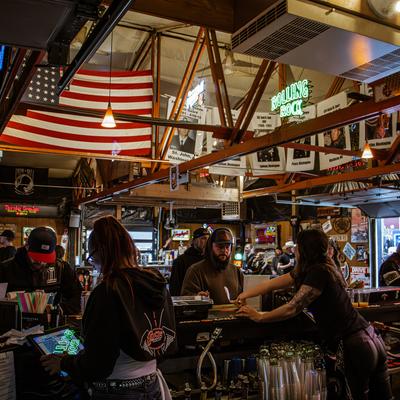 Bartenders helping customers, American flag, neon sign.
