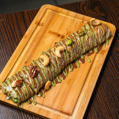Nutella crepe drizzled with sauce and topped with nuts.