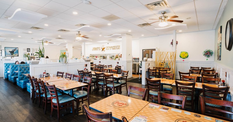 Interior of a diner with blue booths, wooden tables, chairs