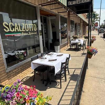 Outdoor sidewalk dining setup with a rectangular table covered by a white tablecloth.