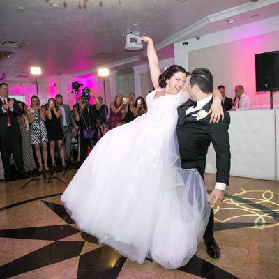 Newlywed couple dancing before gathered guests.