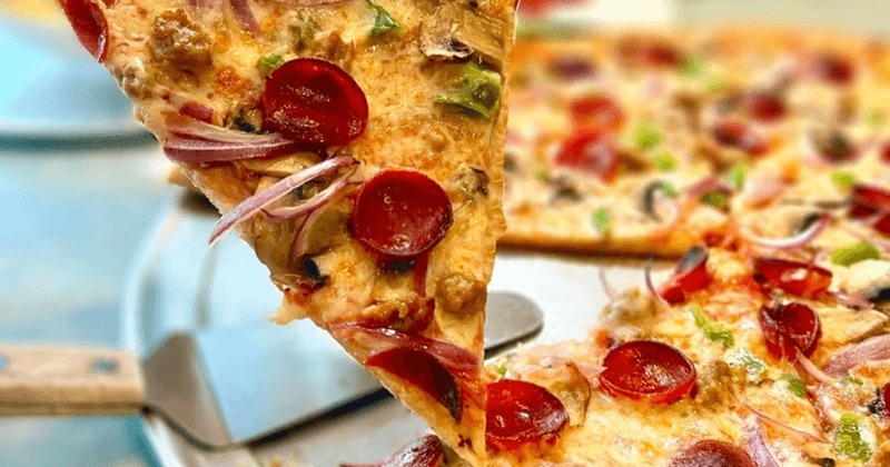 A slice of pizza being lifted from a whole pizza