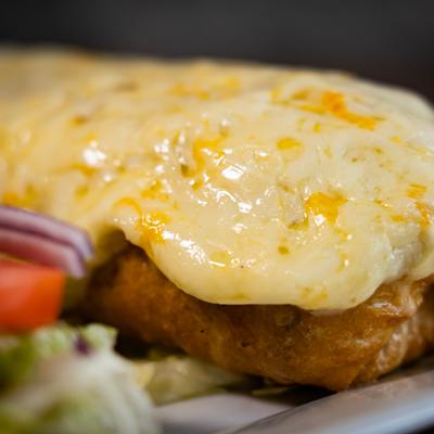 Close-up view of a chimichanga topped with melted cheese.