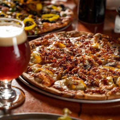 Pizza with four types of cheese and bacon, with a glass of beer on the side