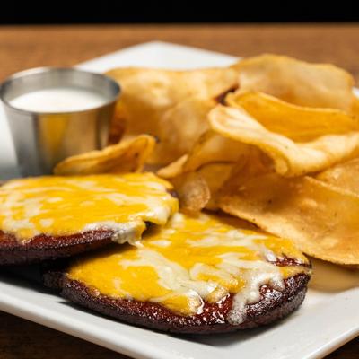 Smoked bologna slices topped with melted cheese, served with chips and a dip.